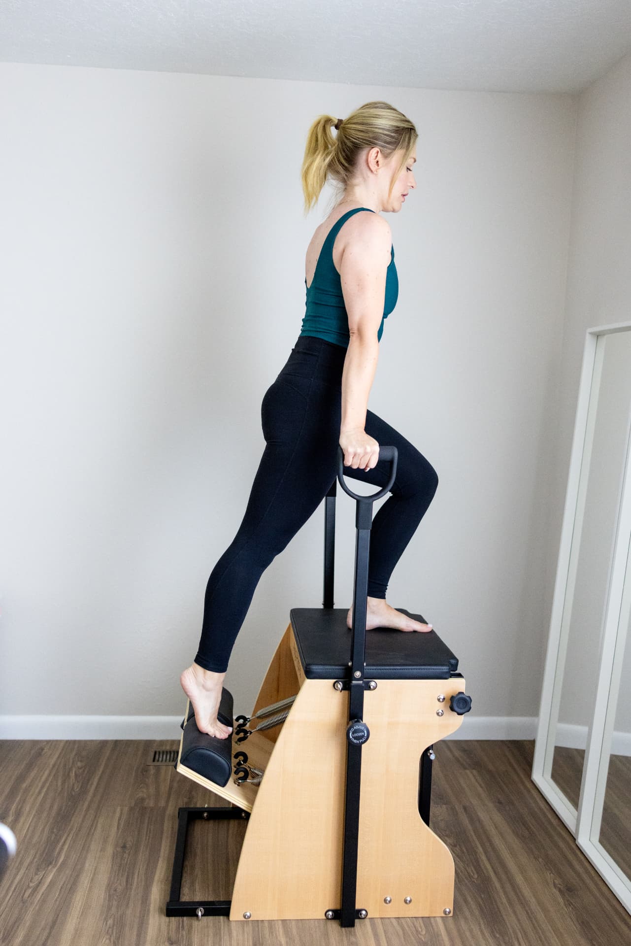 Leah stepping up onto the Pilates chair, holding the handle, during a private session